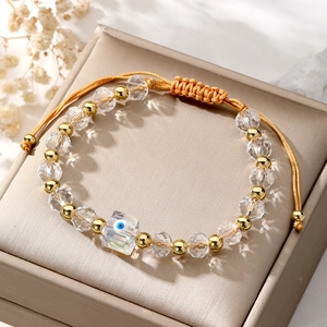 Close-up of a clear crystal evil eye beaded bracelet with gold accents on a gift box