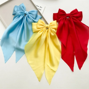 Close-up of vibrant satin bow hair clips with long streamers in blue, yellow, and red