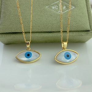 Close-up of golden Figaro chain necklaces featuring mother of pearl evil eye pendants