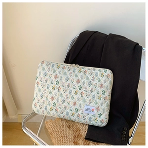 Close-up of quilted floral laptop sleeve with zipper on a chair next to a black blazer