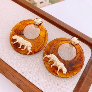 Close-up of retro amber resin hoop earrings with gold metal tiger ornament detail