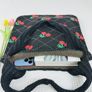 Knitted tote bag with cherry pattern showing interior capacity for phone and book