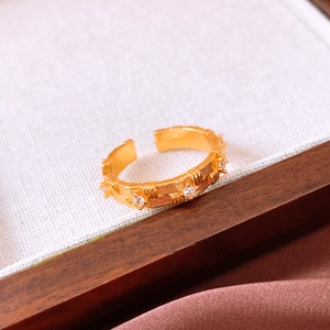 Close-up of golden open ring with brushed texture and tiny crystal stone inlays