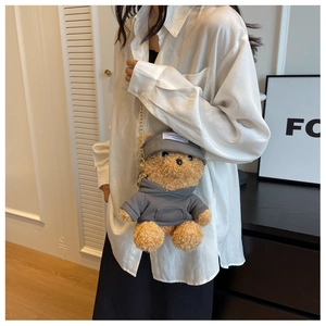 Detail of cute plush bear crossbody bag with gold chain strap on white shirt model