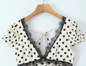 Détail du col en V avec dentelle noire et motif à pois sur ce haut à manches bouffantes
