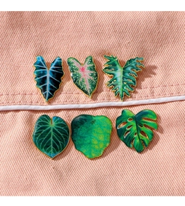 Detailed set of six tropical leaf enamel brooches with golden edges on pink fabric