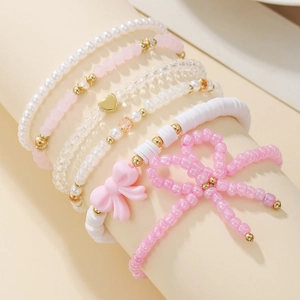 Detail showing a 6-piece stacked pink beaded bracelet set with heart and bow charms
