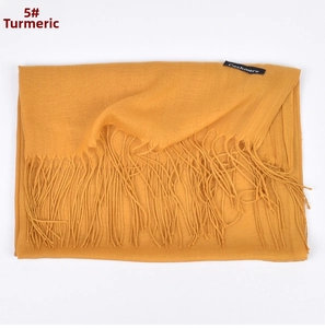 Close-up of ginger yellow cashmere scarf featuring fine fringe and material label