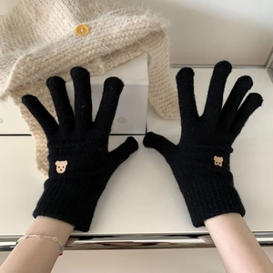 Close-up of black knitted gloves with bear embroidery and touch screen finger design
