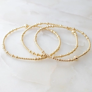 Three-piece set of polished golden bead bracelets with a high-shine mirror finish