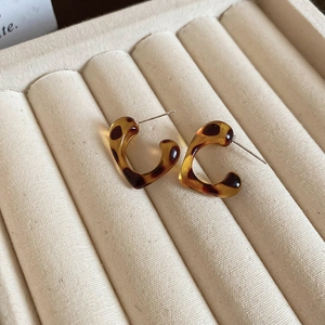 Close-up of heart-shaped leopard print earrings placed in a beige velvet jewelry box