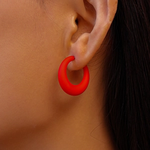 Close-up of red matte acrylic geometric hoop earring worn on a model's ear
