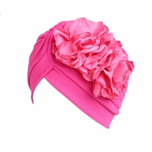 Detail of rose red turban hat with a large 3D flower decoration on soft fabric