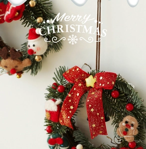 Detailed close-up of a Christmas wreath featuring felt dolls and red glittery bow ornaments