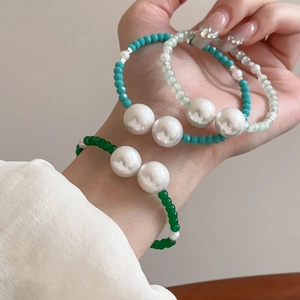Stack of vintage pearl and glass beaded open bracelets with minimalist geometric design