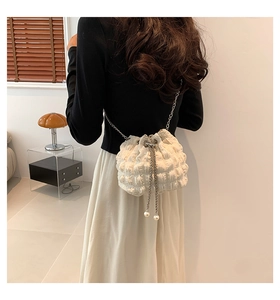 Chic white pleated bucket bag with silver chain strap shown on a model in a modern room