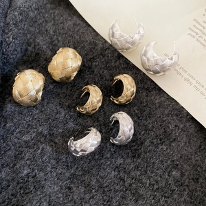 Detailed view of gold and silver woven texture C-shaped earrings and knot studs