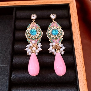 Detail of vintage teardrop earrings with colorful crystals and pearl on black velvet