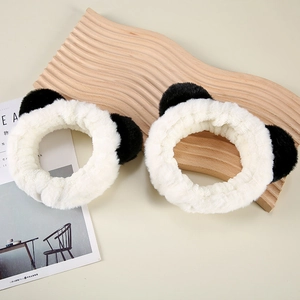 Close-up of plush panda ear headbands on a wooden tray for makeup and skincare