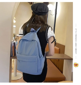 Detail view of large blue nylon backpack with adjustable straps and side pockets on model