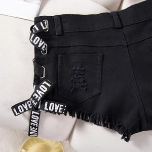 Dettaglio degli shorts in denim nero con nastri stampa LOVE e bordi sfrangiati usurati