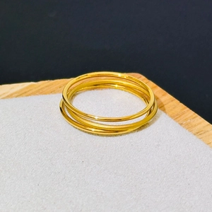 Close-up of three stacked 18k gold plated matte stainless steel rings on a jewelry stand