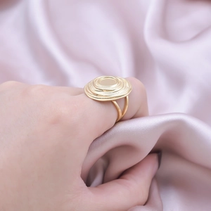 Detail of a gold multilayer spiral ring on pink silk fabric with smooth mirror center