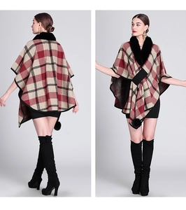 Detail of red and black plaid poncho with faux rabbit fur collar and pompom fringes