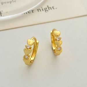 Detail of heart-shaped gold earrings with sparkling zircon stones and snap-on closure