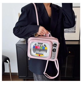 Pink retro TV crossbody bag featuring silver knobs and heart detail on a black blazer