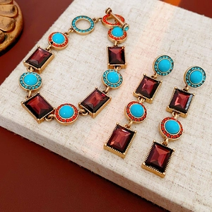 Macro shot of vintage gold bracelet and tassel earrings with wine red and turquoise stones
