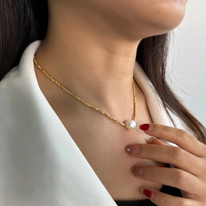 Macro detail of 925 silver golden chain with a large lustrous baroque pearl pendant