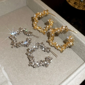 Close-up of sparkling pavé star stud earrings in gold and silver on a jewelry display