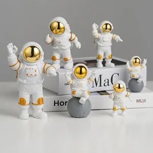 Set of 6 astronaut figurines in white and gold displayed on decorative books
