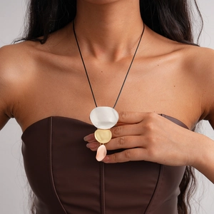 Close-up of a three-tone matte irregular pebble pendant necklace on a leather top