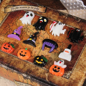 Flat lay of resin Halloween DIY charms including ghosts and pumpkins on a vintage map box