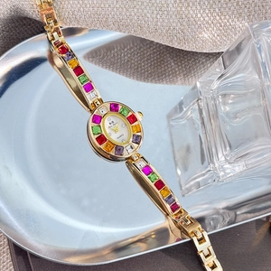 Macro detail of gold ladies watch with colorful rhinestones on a silver platter
