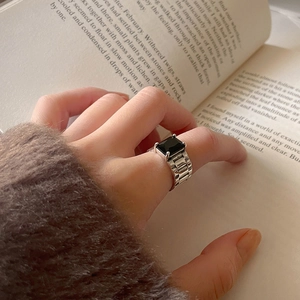 925 silver watch band ring with rectangle black stone displayed on an open vintage book