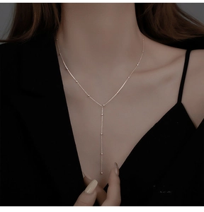 Close-up of elegant gold plated geometric tassel necklace with delicate beads on a model