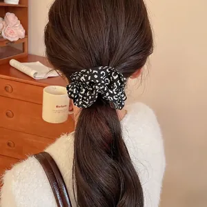 Leopard print fabric scrunchie in black and white worn by a model in a cozy setting