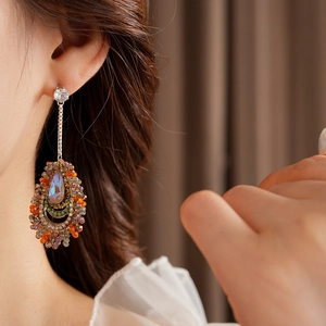 Macro shot of long drop earrings with colorful crystals and sparkling tassels on model