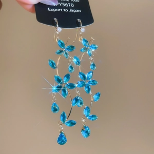 Detail of 925 silver long tassel earrings with blue zircon stones and floral motif
