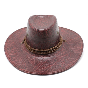 Close-up of deep red western cowboy hat with embossed floral leaf patterns and braided rope