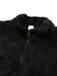 Détail du pull noir à demi-zip montrant la texture gaufrée et l'étiquette de taille M