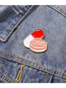 Detail of Relax enamel pin and medical capsule badge on blue denim jacket pocket