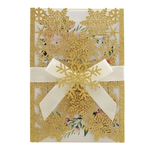 Detail of glitter snowflake laser cut invitation with a wide white satin bow and floral liner