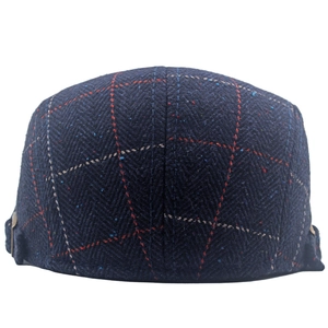 Close-up of navy tweed flat cap showing herringbone texture and colorful fiber accents