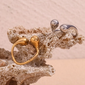 Detailed shot of open teardrop rings in gold and silver finish on coral stone base