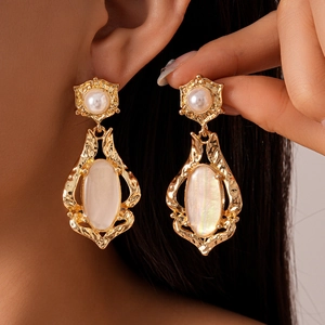 Retro golden shell earrings with oval mother-of-pearl pendant on female model