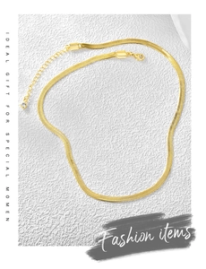 Flat lay of gold snake chain choker with extension chain on white textured background